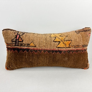 Peut inclure: Un coussin rectangulaire décoratif avec un motif tissé marron et beige. Le coussin présente une section inférieure marron foncé et une section supérieure beige avec des motifs géométriques orange et jaune. Le coussin mesure environ 46 cm de long.
