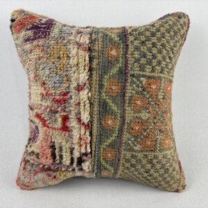 May include: A square cushion with a patchwork design. The cushion is made from a variety of fabrics in shades of red, orange, green, and brown. The cushion has a traditional, vintage look.