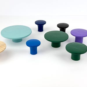 Op de afbeelding: Assortiment van houten knoppen in verschillende kleuren, waaronder blauw, groen, paars en naturel hout. De knoppen zijn rond en hebben een platte bovenkant. Ze zijn perfect om elke kamer een vleugje kleur en stijl te geven.