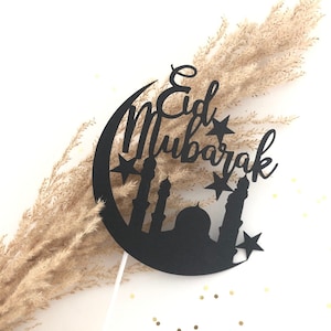 Può includere: Silhouette nera di una luna crescente con stelle e il testo "Eid Mubarak" in un font decorativo. La silhouette della luna include anche una moschea con minareti.