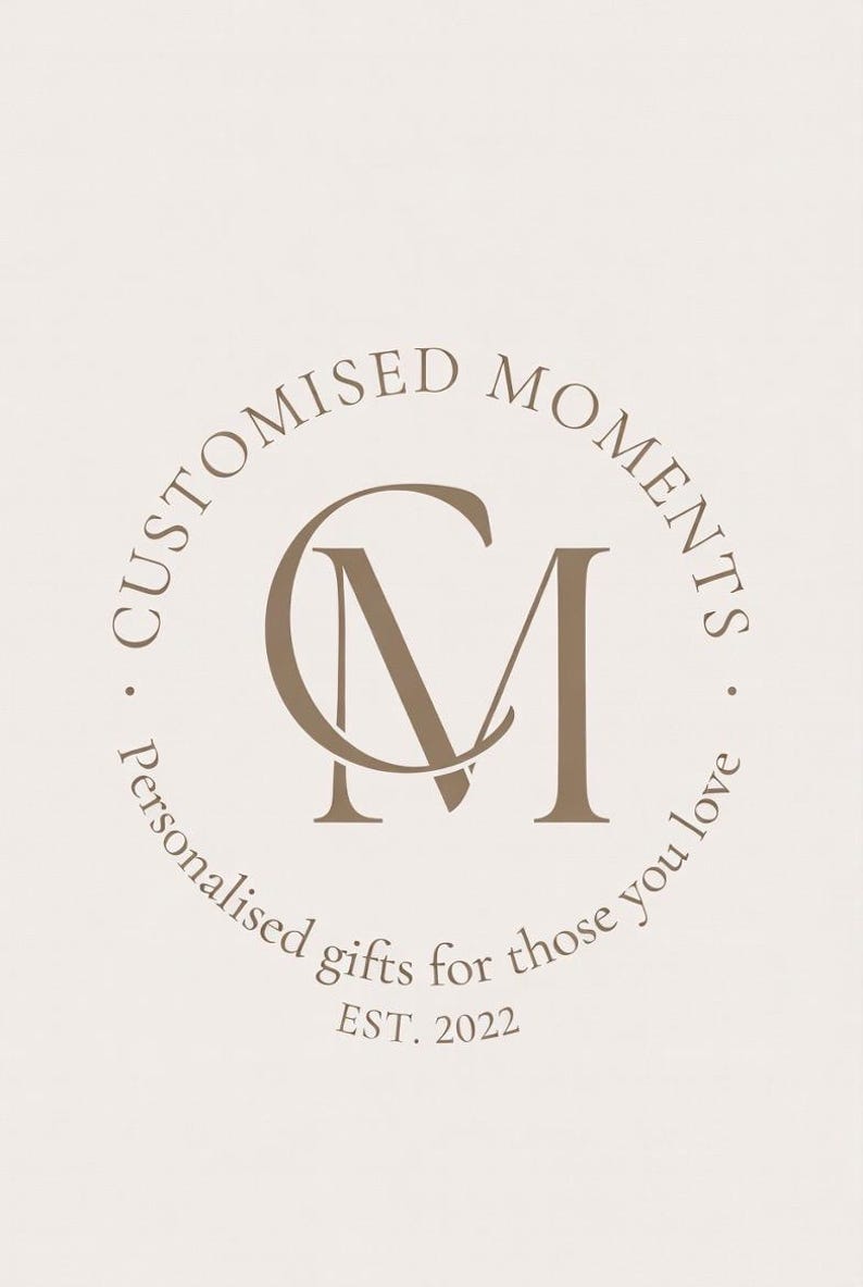 Peut inclure: Un logo circulaire sur fond beige clair pr&eacute;sentant les lettres CM entrelac&eacute;es au centre. Le texte CUSTOMISED MOMENTS est arqu&eacute; au-dessus, tandis que Personalised gifts for those you love est arqu&eacute; en dessous, avec EST. 2022 en bas.