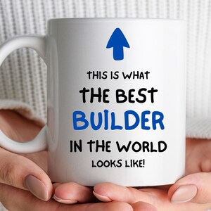 May include: White ceramic mug with a blue arrow pointing up and the text "This is what the best builder in the world looks like!"