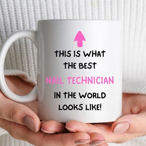 May include: White ceramic mug with a pink arrow pointing up and the text "This is what the best nail technician in the world looks like!"