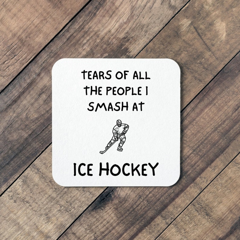 May include: White coaster with black text that reads "Tears of all the people I smash at Ice Hockey". A black and white illustration of an ice hockey player is in the center of the coaster.