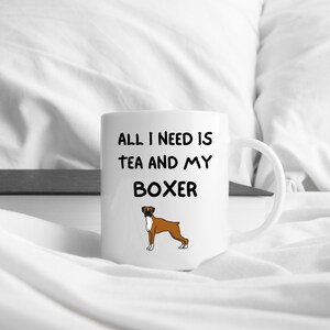 May include: White ceramic mug with black text that reads "All I need is tea and my Boxer". A cartoon image of a brown and white Boxer dog is below the text.