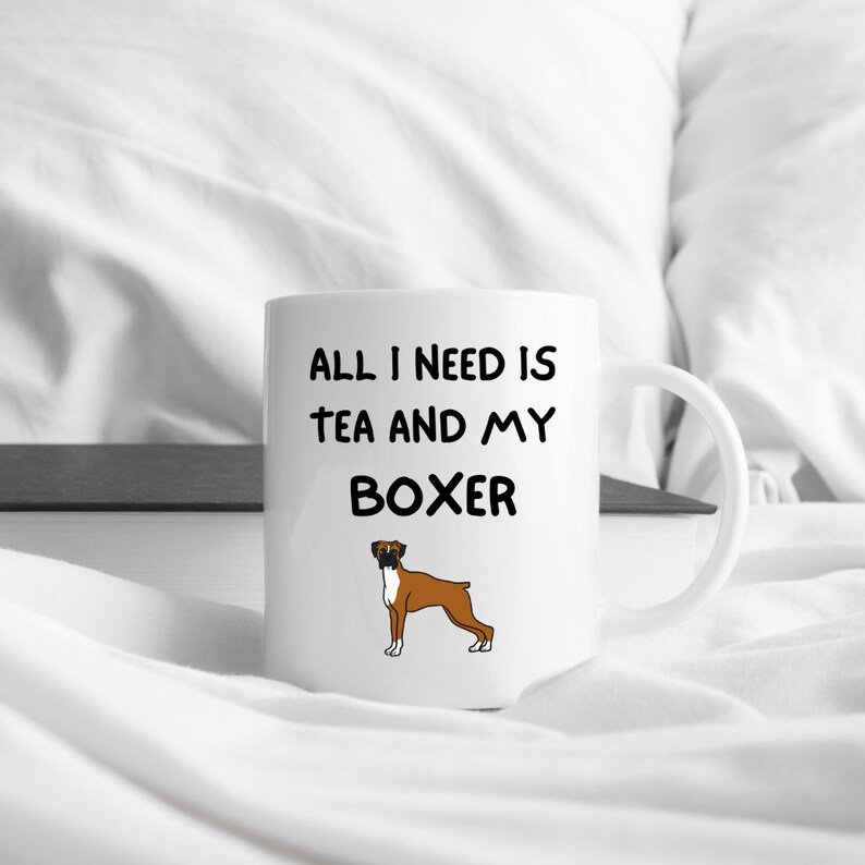 May include: White ceramic mug with black text that reads "All I need is tea and my Boxer". A cartoon image of a brown and white Boxer dog is below the text.