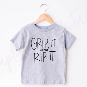May include: A grey short-sleeved t-shirt with the text "Grip it and Rip it" in black.