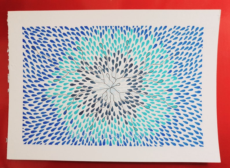 May include: A watercolor painting featuring a central burst of blue and teal teardrop shapes radiating outwards. The artwork has a white background and is set against a red backdrop. The design is symmetrical and detailed.