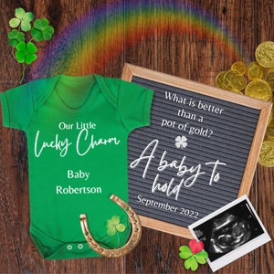Peut inclure: Une grenouillère de bébé verte avec le texte "Our Little Lucky Charm" et "Baby Robertson". Un tableau d'affichage avec le texte "What is better than a pot of gold? A baby to hold September 2022". Un fer à cheval avec un trèfle et une image d'échographie en noir et blanc.
