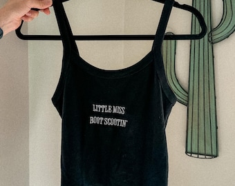 May include: Black tank top with the text "Little Miss Boot Scootin'" in white lettering.