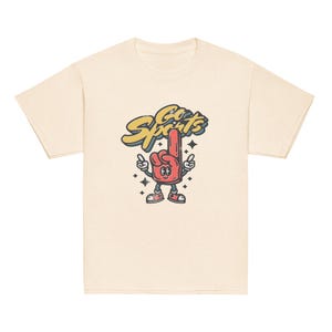 Peut inclure: Un t-shirt cr&egrave;me avec une illustration de dessin anim&eacute; d'un doigt mousse rouge avec un visage et les mots "Go Sports" en lettres jaunes.