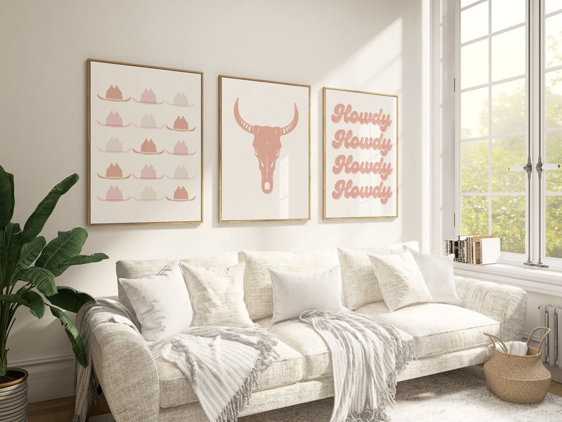 May include: Three framed prints with a western theme. The first print features a pattern of pink cowboy hats. The second print features a pink bull skull. The third print features the word "Howdy" repeated four times in a pink, cursive font.
