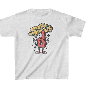 Peut inclure: Un t-shirt gris avec une illustration de dessin anim&eacute; d'un doigt en mousse rouge avec un visage et le texte "Go Sports" en jaune et bleu.