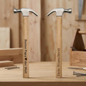 Könnte beinhalten: Zwei Klauenhammer mit Holzgriffen und silbernen Köpfen. Ein Hammer hat den Text "Bester Papa der Welt" und ein Herzsymbol. Der andere Hammer hat den Text "Dein Wunschtext". Die Hämmer liegen auf einer Holzoberfläche.