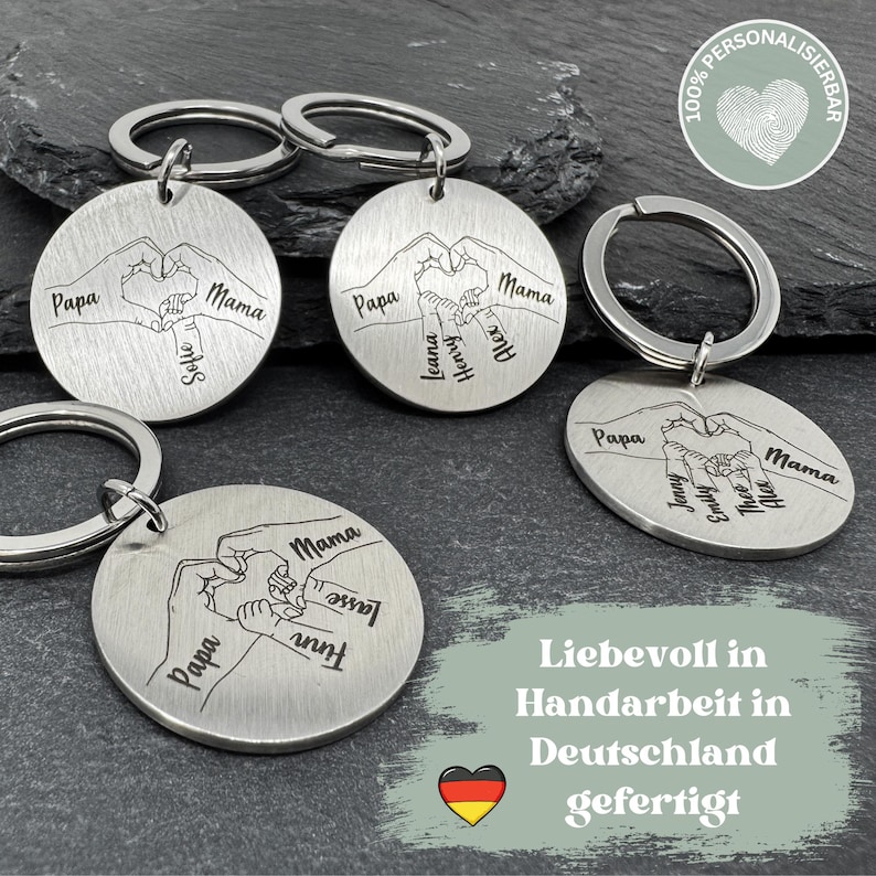 May include: Four silver keychains with interlocking hands and personalized names. Each keychain features a heart shape formed by the hands. The keychains are displayed on a gray background with the text "Liebevoll in Handarbeit in Deutschland gefertigt" and a German flag.