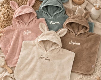 May include: Four hooded towels with animal ears in dusty pink, sage green, brown, and cream. Each towel features embroidered names: Sofia, Lucas, Joshua, and Amelie. The towels are made of soft terry cloth fabric and include a small tag on the bottom corner.