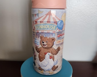 May include: A colorful water bottle with a circus-themed design. The bottle features a light blue lid and a pink body. The design includes a bear, a chicken, and the word "FUNHOUSE".