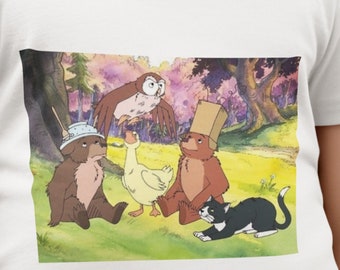 May include: A white t-shirt with a cartoon image of a brown bear wearing a blue bowl on its head, a brown bear wearing a brown paper bag on its head, a yellow duck, and a black and white cat. The animals are in a forest setting with green trees and pink flowers.