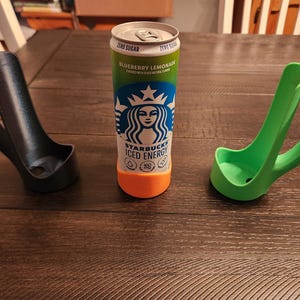 May include: A can of Starbucks Iced Energy Blueberry Lemonade with a green and orange base, next to a black and a green can holder. The can holders have a handle for easy carrying.