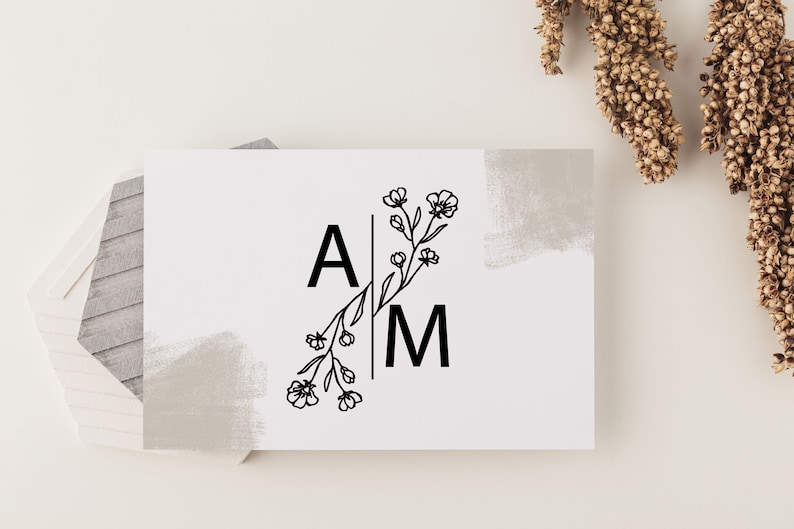 May include: A white card with a black floral design and the letters "A" and "M" on either side of the floral design. The card has a gray painted background.