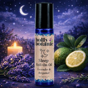 May include: A blue glass roll-on bottle with a black cap, labeled "Sleep Roll-On Oil Lavender & Bergamot." The label features a crescent moon and stars. The background includes a lit candle, lavender, and citrus fruits, with a night sky.
