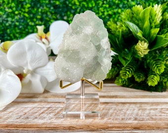 Op de afbeelding: Een groene en witte fluorietkristalcluster op een heldere acrylstandaard met een gouden metalen basis.