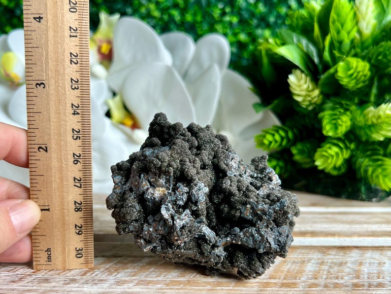 Op de afbeelding: Een cluster van zwarte en zilveren dendritische agaat, ongeveer 6,5 cm lang. De agaat heeft een ruw, getextureerd oppervlak en is een natuurlijke kristal.
