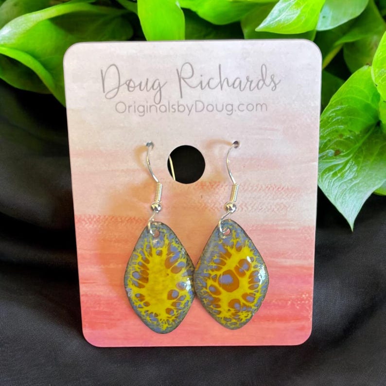 May include: A pair of silver dangle earrings with a yellow and blue abstract design. The earrings are on a card that says "Doug Richards OriginalsbyDoug.com".