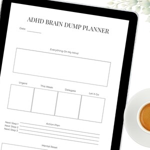 May include: A digital planner on a tablet with the text "ADHD BRAIN DUMP PLANNER." The planner includes sections for "Everything On My Mind," "Urgent," "This Week," "Delegate," and "Let it Go." A cup of coffee sits on a saucer in the bottom right corner.