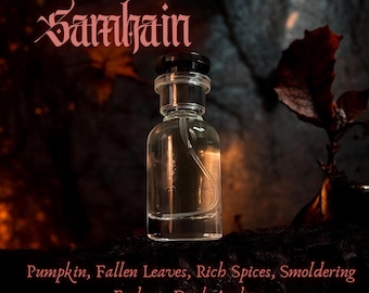 Può includere: Un flacone di profumo in vetro trasparente con tappo nero, che riporta il testo 'Freyja's Daughters Samhain' in alto e 'Pumpkin, Fallen Leaves, Rich Spices, Smoldering Embers, Dark Amber' in basso, su uno sfondo scuro e suggestivo.