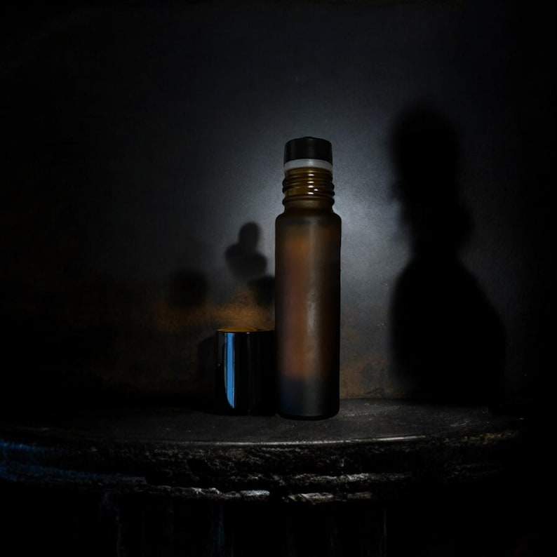 Peut inclure: Une bouteille en verre marron avec un bouchon noir et blanc et une petite tasse noire. La bouteille a un aspect givr&eacute;. Les objets sont pos&eacute;s sur un fond sombre. La bouteille mesure environ 15 cm de haut.
