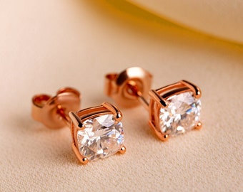 May include: A pair of rose gold stud earrings with clear square-shaped cubic zirconia stones.