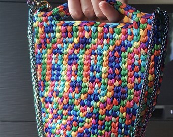 May include: A small, colourful crocheted bag with a rainbow pattern and a silver chain strap.