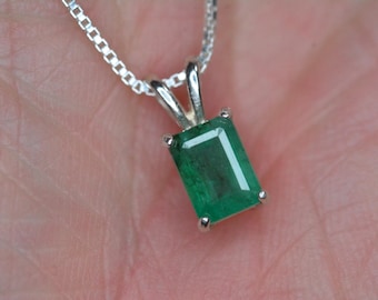 Op de afbeelding: Een rechthoekige smaragd hanger ketting met een zilveren ketting. De smaragd heeft een levendige groene kleur en is gezet in een zilveren bezel. De hanger is ongeveer 1,3 cm lang.