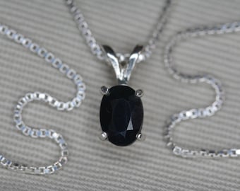 Op de afbeelding: Een zilveren ketting met een hanger met een zwarte ovale edelsteen.