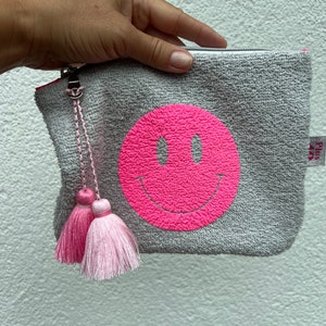 Kleines Kosmetiktäschchen aus hellgrauem Frottee mit lustigem Neonsmileydruck und hübscher Quaste.