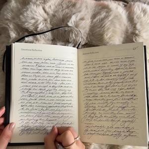 Puede incluir: Diario abierto con cubierta negra y p&aacute;ginas rayadas. Las p&aacute;ginas est&aacute;n llenas de texto escrito a mano con tinta negra. El diario est&aacute; abierto en dos p&aacute;ginas, una titulada "Reflexi&oacute;n emocional" y la otra titulada "Reflexi&oacute;n racional".