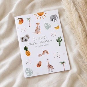 Op de afbeelding: Een witte omslag van een boekje met aquarelillustraties van een koala, jachtluipaard, olifant, giraf, ananas, mango, papaja, banaan, palmbomen, cactus, zon en regenbogen. De tekst luidt U-Heft, Thilo Müller en 30. März 2022.