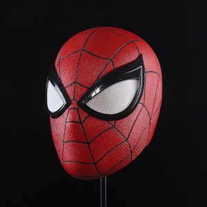 Puede incluir: Una m&aacute;scara de Spider-Man roja y negra con una cubierta de ojo de malla blanca.
