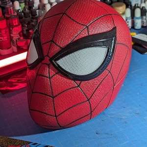 Puede incluir: Una m&aacute;scara de Spider-Man roja y negra con una pieza de ojo de malla blanca. La m&aacute;scara tiene una superficie texturizada y est&aacute; hecha de un material duradero.