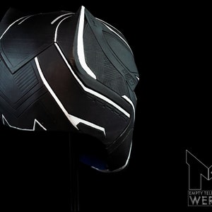 K&ouml;nnte beinhalten: Schwarze und wei&szlig;e Plastikmaske von Black Panther mit strukturierter Oberfl&auml;che. Die Maske ist seitlich geneigt und zeigt das Profil des Charakters.