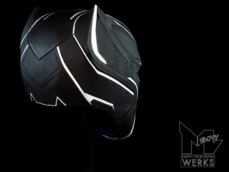 K&ouml;nnte beinhalten: Schwarze und wei&szlig;e Plastikmaske von Black Panther mit strukturierter Oberfl&auml;che. Die Maske ist seitlich geneigt und zeigt das Profil des Charakters.