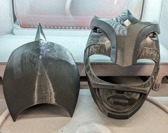 Puede incluir: Dos máscaras de plástico negro impresas en 3D. Una máscara es una máscara completa con una parte superior puntiaguda y un diseño detallado. La otra máscara es una media máscara que cubre la frente y la parte superior de la cabeza.