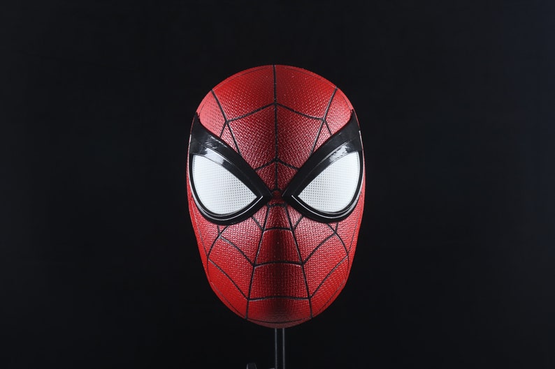 Puede incluir: Una m&aacute;scara de Spider-Man roja y negra con ojos blancos. La m&aacute;scara est&aacute; hecha de un material texturizado y tiene un dise&ntilde;o de telara&ntilde;a.