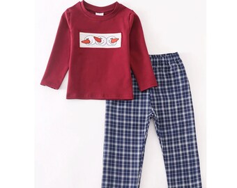 May include: A two-piece baby outfit with a long-sleeved red shirt featuring an embroidered snowman design and blue and white plaid pants.