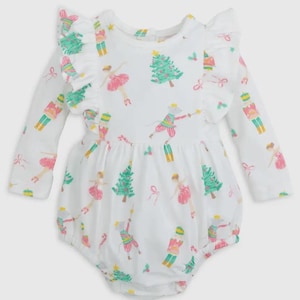 May include: White long-sleeved baby onesie with a festive Christmas print featuring ballerinas, nutcrackers, and Christmas trees. The onesie has a ruffled neckline and a bubble hem.