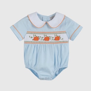 May include: Pale blue baby romper with a white collar and orange trim. The romper has a smocked panel with embroidered orange pumpkins and green vines. The short-sleeved romper is designed for comfort and style.