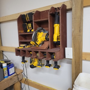 May include: A wooden wall-mounted storage rack with a variety of power tools, including a circular saw, a reciprocating saw, and several drills. The tools are all yellow and black and are organized in a neat and tidy manner.