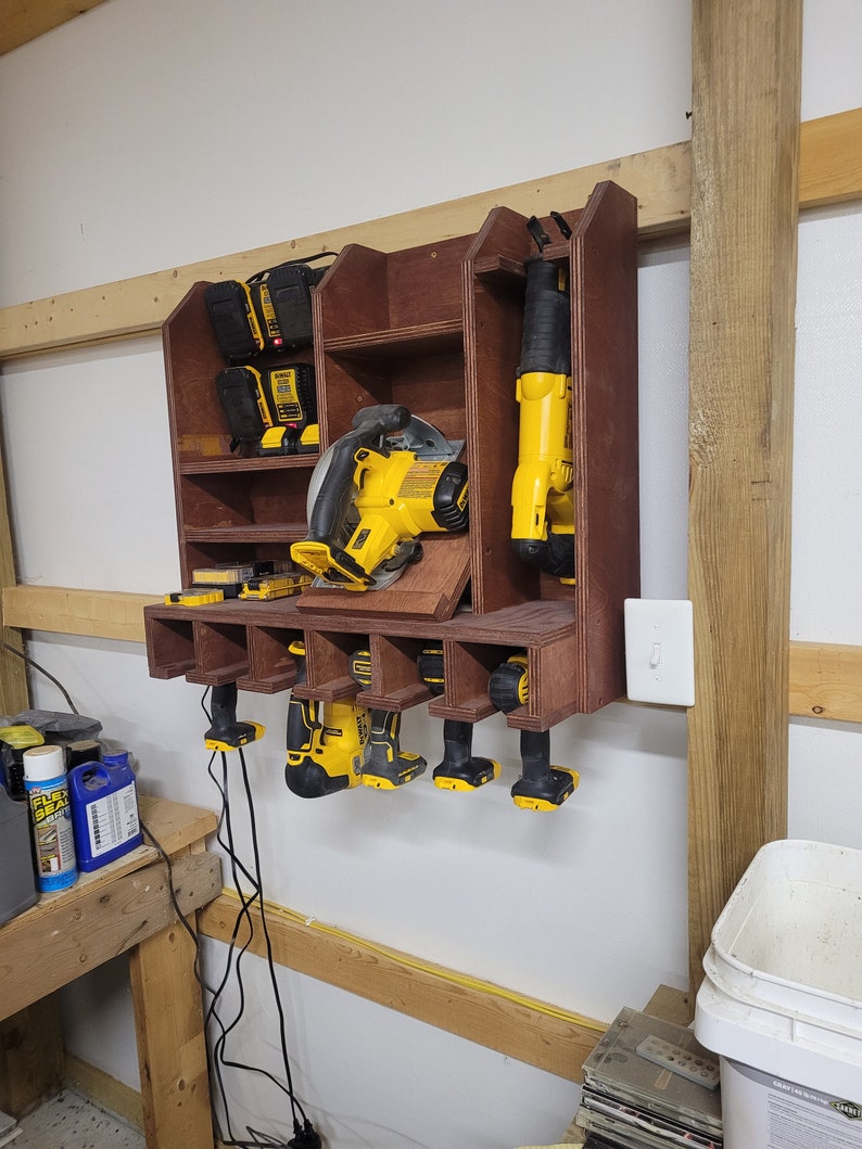 May include: A wooden wall-mounted storage rack with a variety of power tools, including a circular saw, a reciprocating saw, and several drills. The tools are all yellow and black and are organized in a neat and tidy manner.