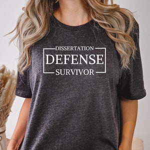 May include: A dark gray t-shirt with the text "DISSERTATION DEFENSE SURVIVOR" printed in white.